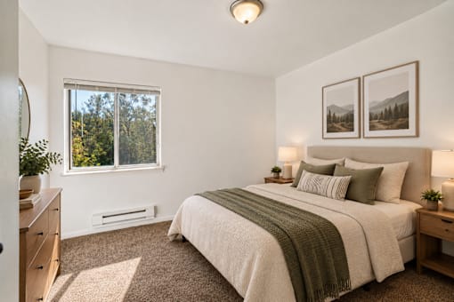 A bedroom with a large bed and a window overlooking trees.
