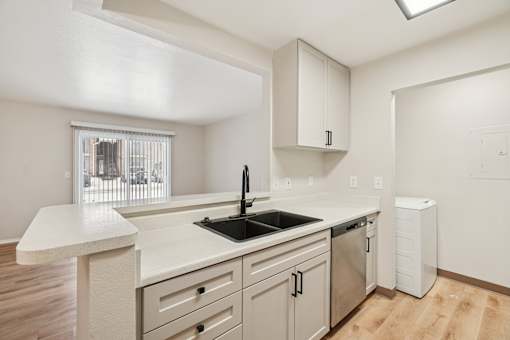 A kitchen with a white counter top and a window.
