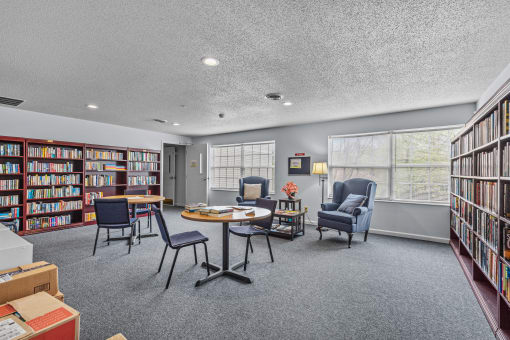 a library with a round table and chairs