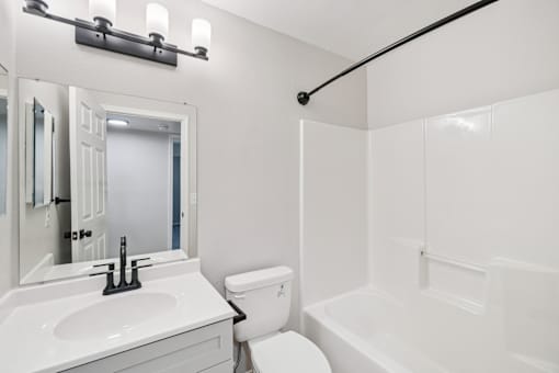A white bathroom with a toilet, sink, and bathtub.