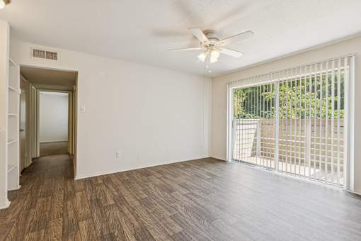 A room with a ceiling fan and sliding glass doors.