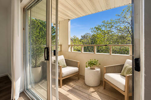A patio with a sliding glass door leading to a balcony with a white couch and a potted plant.