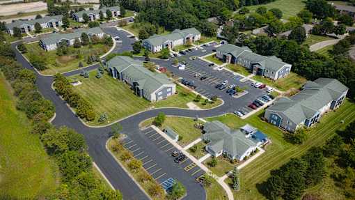 A bird's eye view of a parking lot surrounded by green grass and buildings.