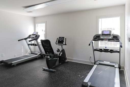 A room with a treadmill, a stationary bike, and a rowing machine.