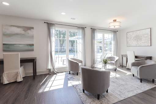 A living room with a grey sofa, a white chair, and a painting on the wall.