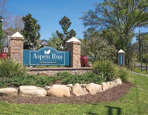 A sign that says "Aspen Run" is in front of a grassy area.