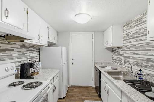 A kitchen with white cabinets and a white stove top oven.