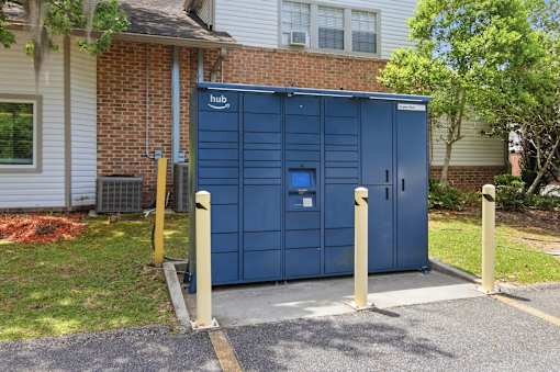 A blue porta potty is parked in front of a brick building.