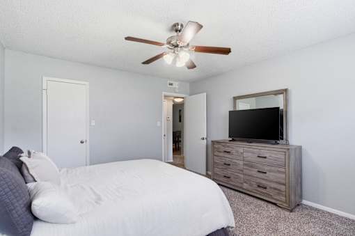 A bedroom with a bed, dresser, and television.
