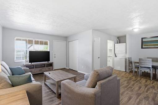 A living room with a couch, chairs, and a television.