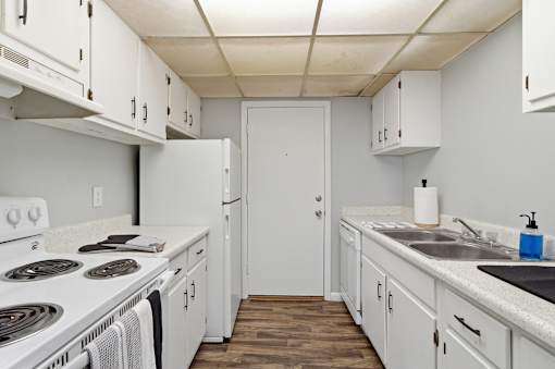 A kitchen with white cabinets and a white door.