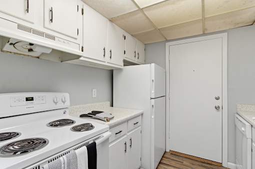 A white kitchen with a stove top oven and a refrigerator.