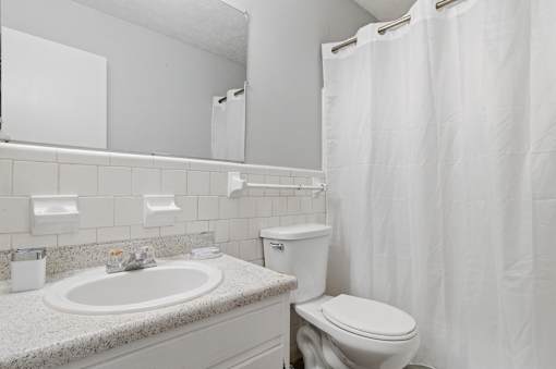 A white bathroom with a toilet, sink, and shower curtain.