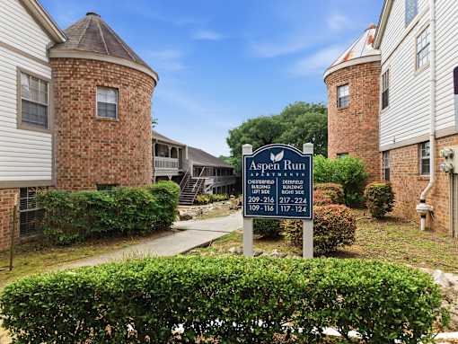 A sign for Aspen Run Apartment Homes is in front of a building.