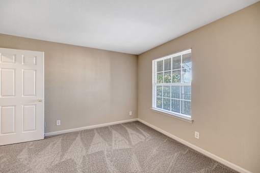 Bright apartment room with white door and window overlooking trees at Cambury Hills Apartments in Omaha, Nebraska