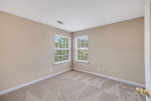 Bright and spacious carpeted bedroom with two windows at Cambury Hills Apartments in Omaha, Nebraska