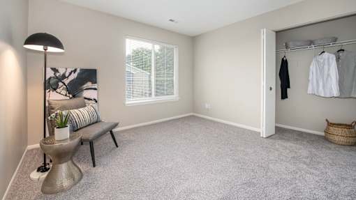 A room with a grey carpet and a grey wall with a white door.