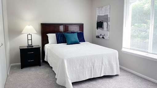 A bedroom with a bed, nightstand, and window.