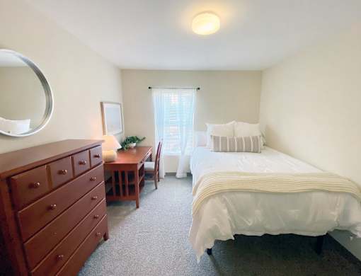 A bedroom with a bed, dresser, and mirror.