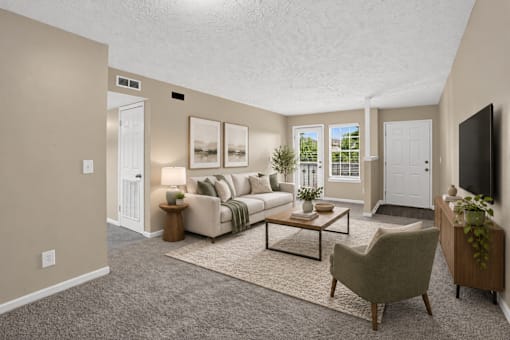 Virtually staged living room with a couch, chair, and television at Arbours at Victoria Place in Prattville, AL