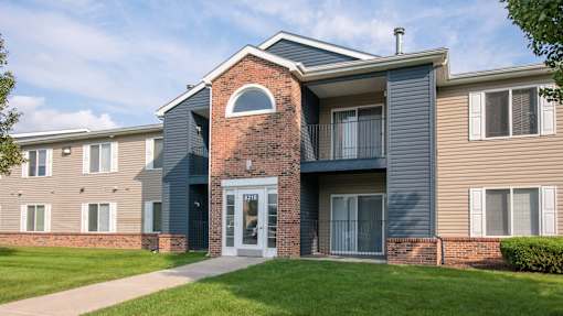 A modern two-story apartment building with a brick archway entrance.