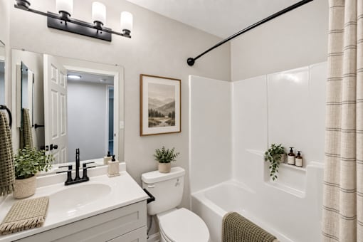 A white bathroom with a toilet, sink, and a shower.