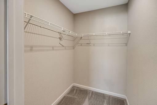 Spacious empty white closet with built-in shelves and carpeted stairway at Cambury Hills Apartments in Omaha, Nebraska