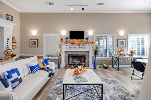 Cozy community clubhouse living room with fireplace and white couch at Cambury Hills Apartments in Omaha, Nebraska