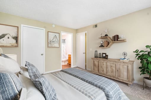 A bedroom with a bed, a dresser, and a plant.
