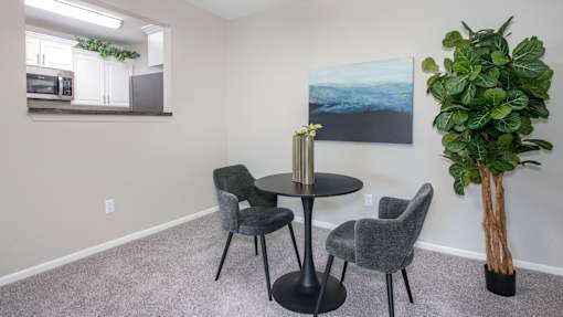 A grey table surrounded by grey chairs in a room with a painting on the wall.