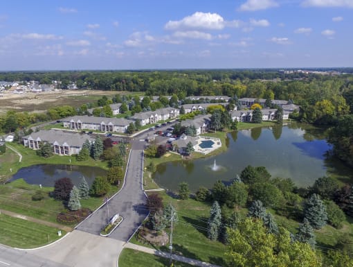 an aerial view of a community with a pond and trees