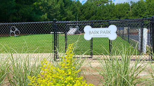 A sign that says Bark Park is in front of a fence.
