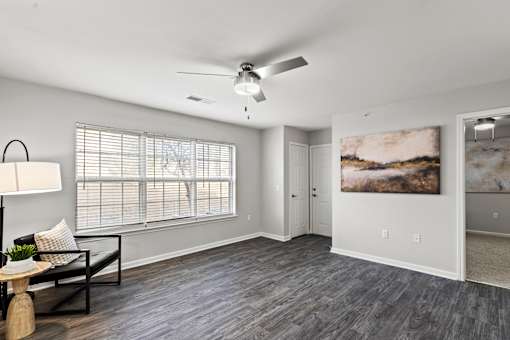 A living room with a ceiling fan and a painting on the wall.