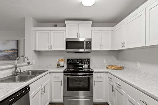 A kitchen with white cabinets and a black stove top oven.
