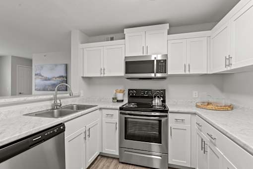 A modern kitchen with white cabinets and stainless steel appliances.