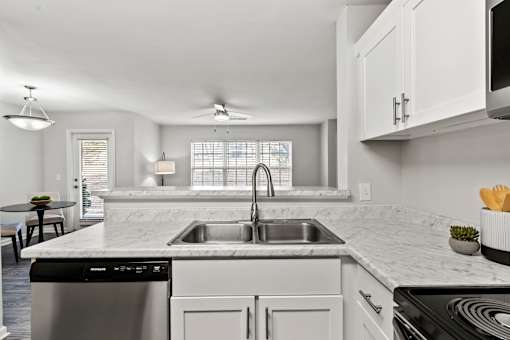 A modern kitchen with a marble countertop and stainless steel appliances.