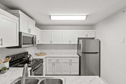 A kitchen with white cabinets and appliances.