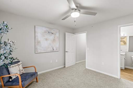 A room with a ceiling fan and a painting on the wall.