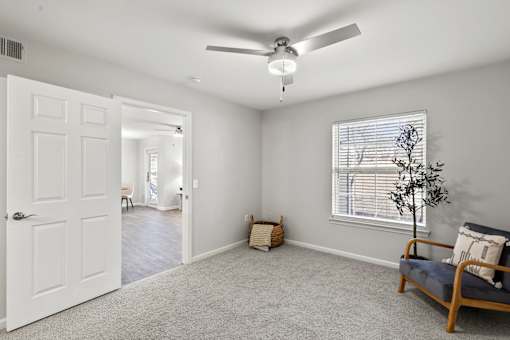 A room with a ceiling fan and a window with blinds.