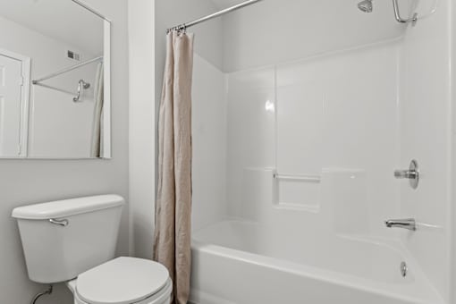 A white toilet sits next to a white bathtub in a bathroom.