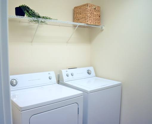 Two white front loading washing machines in a laundry room.