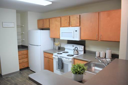 A kitchen with a white refrigerator, white oven, and brown cabinets.