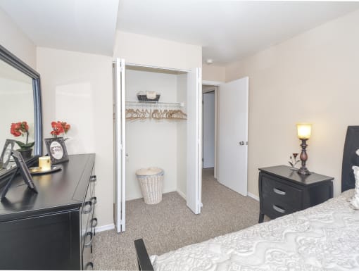 a bedroom with a closet and a bed and a desk with a mirror and a