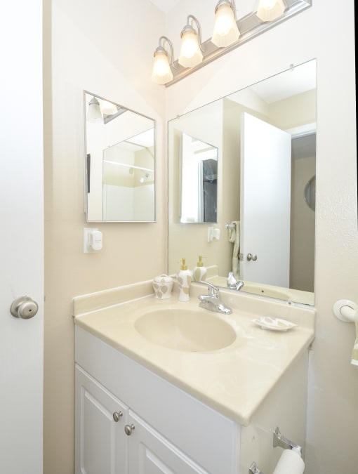 a white bathroom with a sink and two mirrors