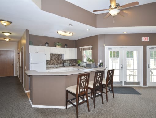 a kitchen with a counter and chairs and a ceiling fan