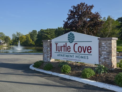 the sign for turtle cove apartment homes in front of a fountain