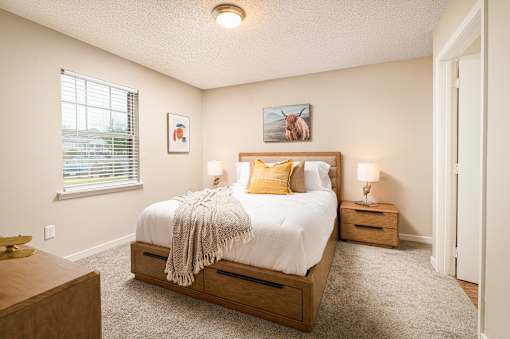 Bright bedroom with bed, nightstands, and window at Southwind Apartments in Richland, MS.