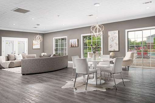 Modern community room with grey sofa, white chairs, and wood flooring at Southwind Apartments in Richland, MS.