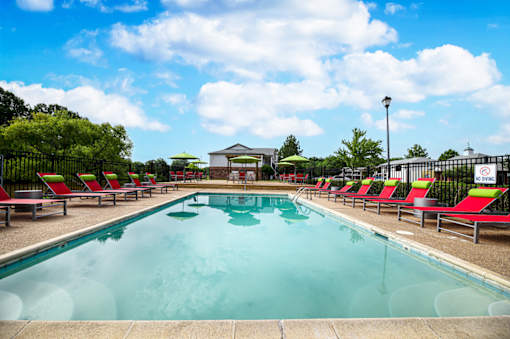 Spacious outdoor pool lined with red lounge chairs at Southwind Apartments in Richland, MS.