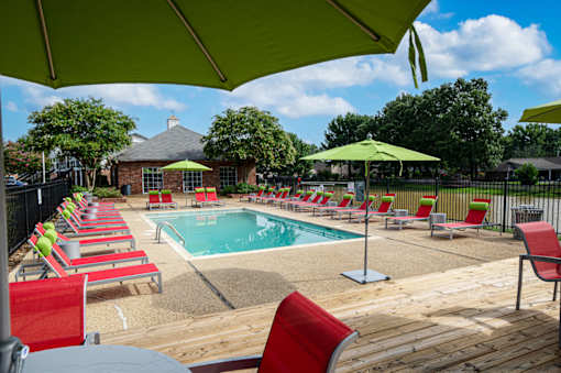 Community pool area with red chairs and green umbrellas at Southwind Apartments in Richland, MS.